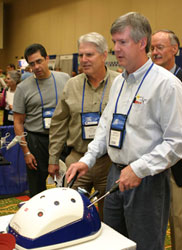 A conference participant manipulates a surgical simulation device in the exhibit hall.